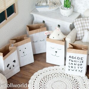May include: Four brown paper bags with different designs. The bags have black and white drawings of a panda, a bear, eyes, and the alphabet. The bags are sitting on a wooden floor.