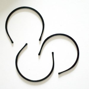 May include: Three black plastic headbands, arranged in a triangular shape on a white background.