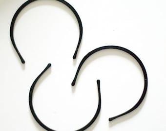 May include: Three black plastic headbands, arranged in a triangular shape on a white background.