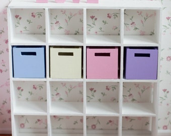 May include: White cube shelf unit with four colorful storage boxes. The boxes are light blue, cream, pink, and purple. The word "LOVE" is spelled out in pink letters above the shelf.