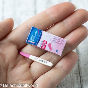 Może przedstawiać: Różowo-biały test ciążowy z napisem "First Response" i "6 Days Early" na opakowaniu. Test znajduje się w dłoni osoby.