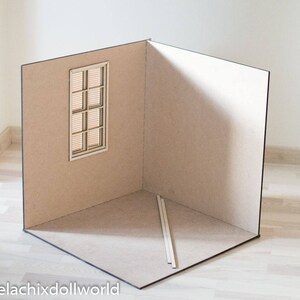 May include: A cardboard room box with a window and two wooden dowels. The room box is beige and has a black border.