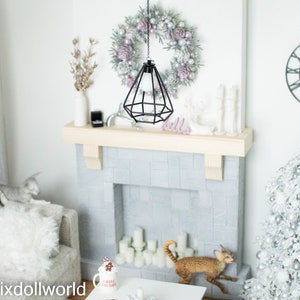 May include: A miniature dollhouse living room with a white fireplace, a white Christmas tree decorated with silver ornaments, a white couch, and a black pendant light hanging above a white wreath.
