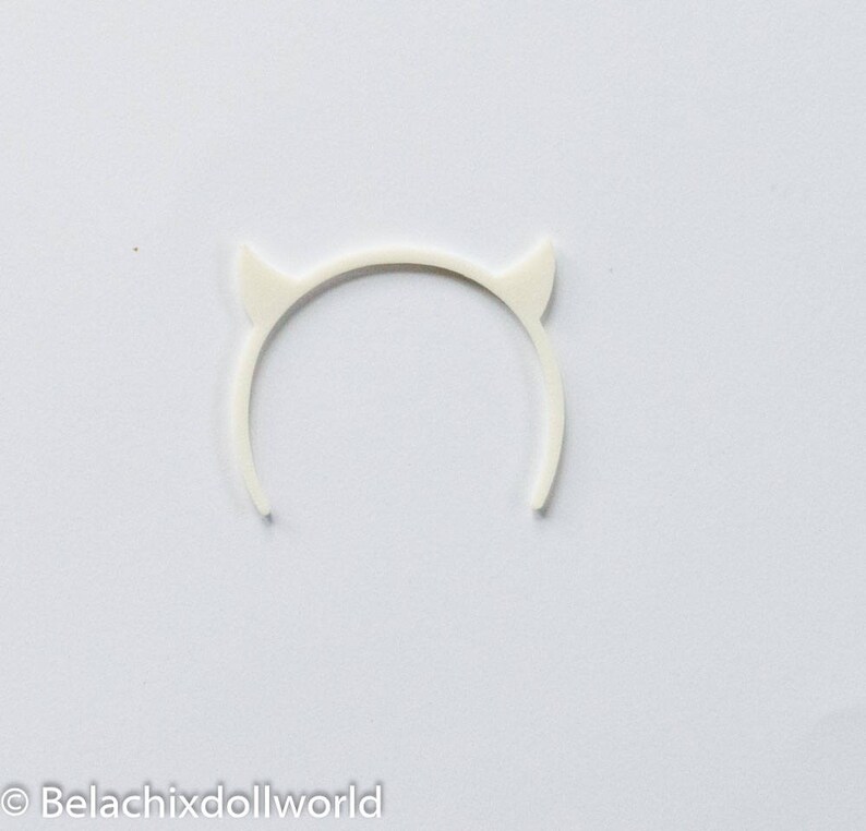 May include: White plastic devil horn headband. The headband is a simple circle with two small horns on the top.