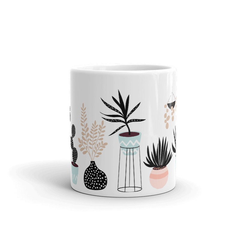 May include: White ceramic mug with a black and white illustration of potted plants. The plants are in various styles and colors, including a cactus, a fern, and a succulent.