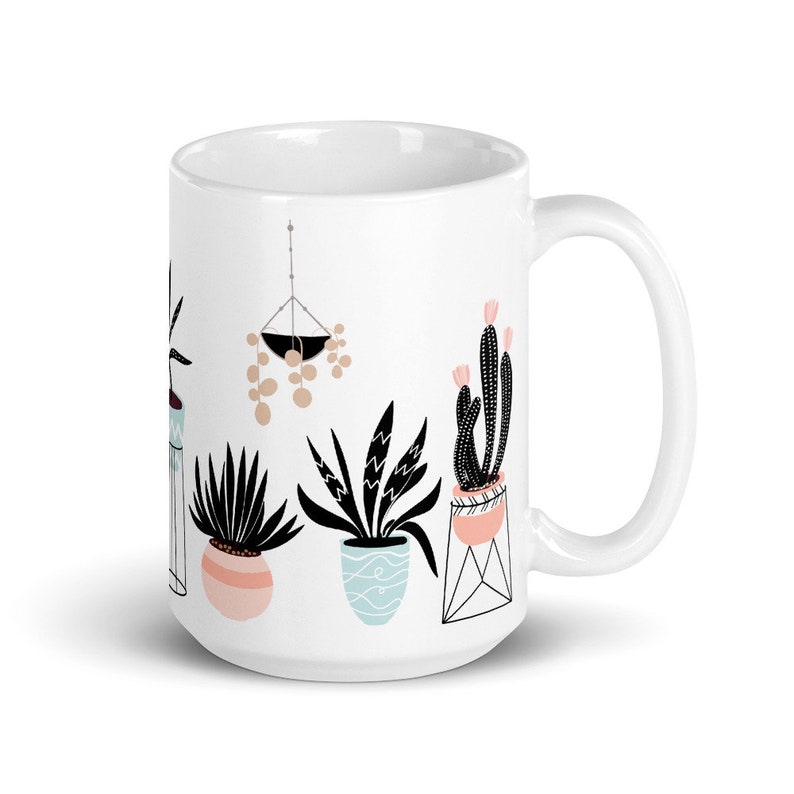 May include: White ceramic mug with a black and white illustration of potted plants. The plants include a cactus, a succulent, and a fern. The mug has a black handle.
