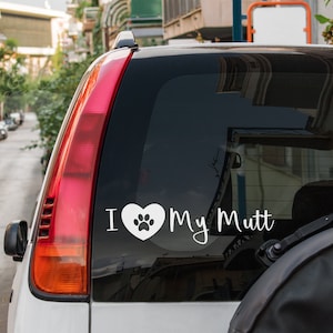 May include: A white car with a rear window sticker that says "I love my mutt" with a paw print inside a heart.