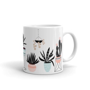May include: White ceramic mug with a black and white illustration of potted plants and a hanging planter with round shapes. The plants are in various styles and colors, including a cactus, a succulent, and a fern.
