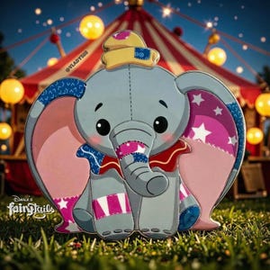 May include: A cartoon-style elephant pin with large pink ears, wearing a yellow hat and a red collar. The elephant is gray with patches of blue, pink, and white. The pin is set against a background of a circus tent and grass. The text "Darla's Fairytails" is visible.