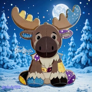 Könnte beinhalten: Ein Plüsch-Elch-Anstecknadel mit braunem Körper, großen Geweihen und blauen, gelben und lila Patches. Die Anstecknadel hat ein cartoonartiges Design mit dem Text "Darla's Fairytails" vor einem verschneiten Winterhintergrund.