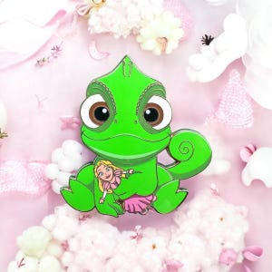 Puede incluir: Personaje de dibujos animados de camaleón verde con grandes ojos marrones que sostiene una pequeña muñeca de princesa rubia con un vestido rosa.