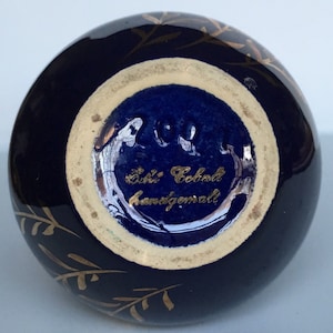 May include: A cobalt blue ceramic vase with gold leaf detailing and a gold inscription that reads "Echt Kobalt handgemalt".