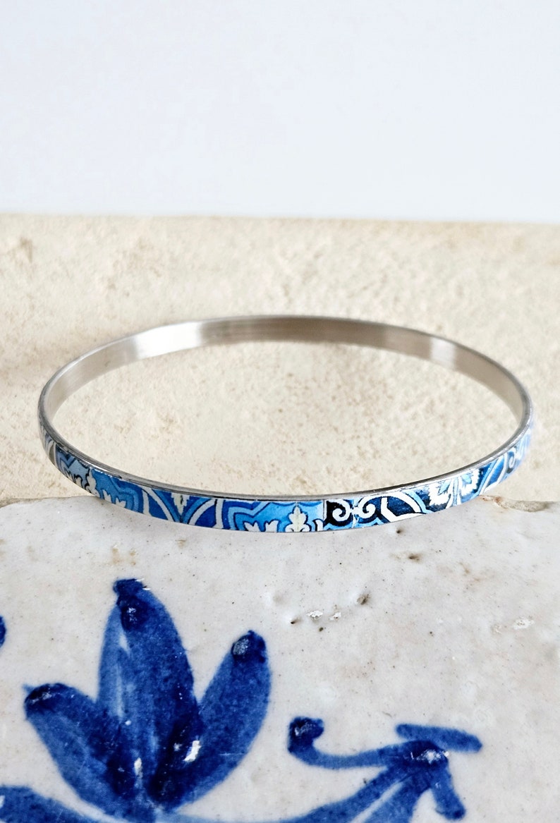 May include: A silver bangle bracelet with a blue and white patterned design.