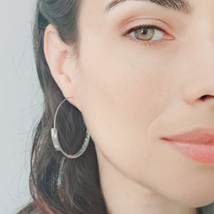 K&ouml;nnte beinhalten: Nahaufnahme eines Frauen Gesichts mit silbernen Creolen. Die Ohrringe sind schlicht und elegant und unterstreichen die nat&uuml;rliche Sch&ouml;nheit der Frau.