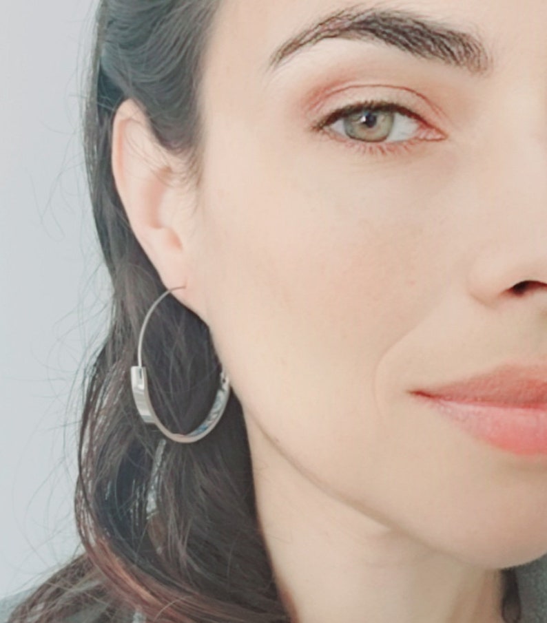 K&ouml;nnte beinhalten: Nahaufnahme eines Frauen Gesichts mit silbernen Creolen. Die Ohrringe sind schlicht und elegant und unterstreichen die nat&uuml;rliche Sch&ouml;nheit der Frau.