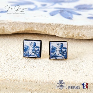 Peut inclure: Une paire de boucles d'oreilles carrées avec un cadre doré et une image bleue et blanche d'un ange à l'intérieur. Les boucles d'oreilles sont faites à la main en France.