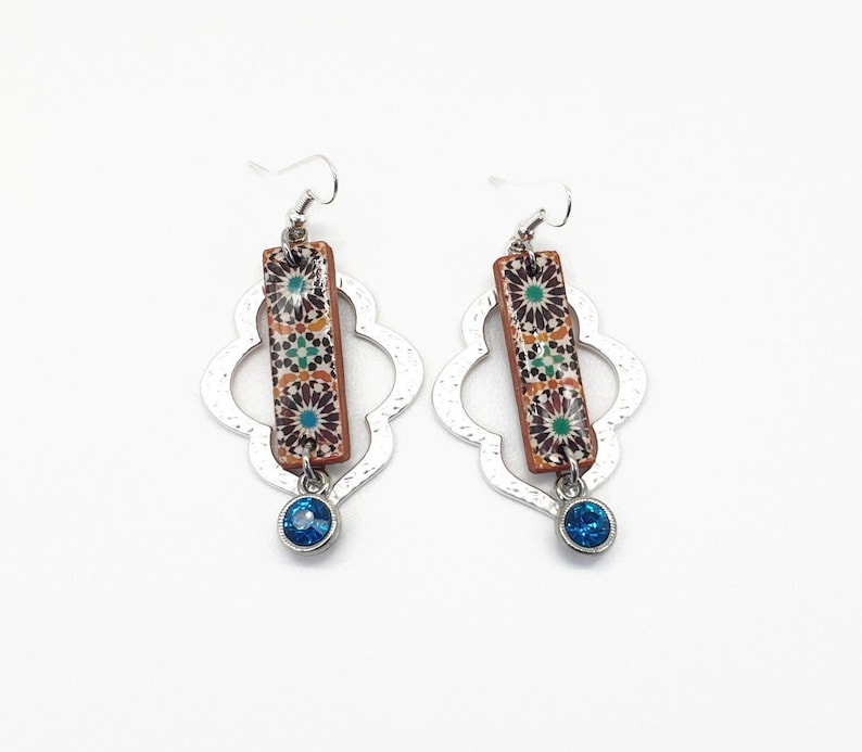Peut inclure: Une paire de boucles d'oreilles argent&eacute;es avec un pendentif en forme de goutte de pierre bleue. Les boucles d'oreilles pr&eacute;sentent un pendentif rectangulaire avec un motif g&eacute;om&eacute;trique color&eacute;.