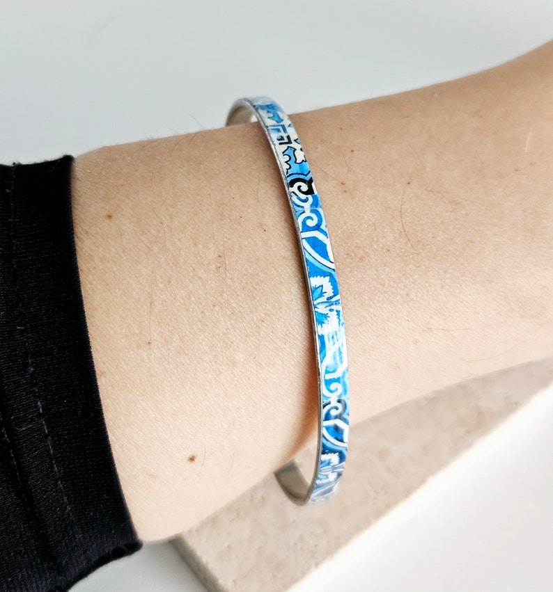 May include: A silver bangle bracelet with a blue and white patterned design.