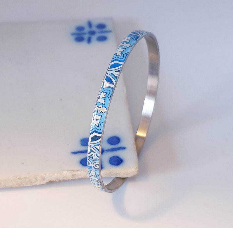 May include: A silver bangle bracelet with a blue and white patterned design.