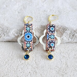 Peut inclure: Une paire de boucles d'oreilles en or avec un motif de carrelage bleu et blanc et un pendentif en pierre pr&eacute;cieuse bleue.