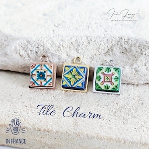May include: Three square tile charms with different colorful patterns. The charms are made of metal and have a loop at the top for attaching to a necklace or bracelet. The charms are on a white background.