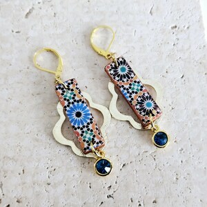 Peut inclure: Une paire de boucles d'oreilles en or avec un motif g&eacute;om&eacute;trique bleu et orange et un pendentif en cristal bleu.