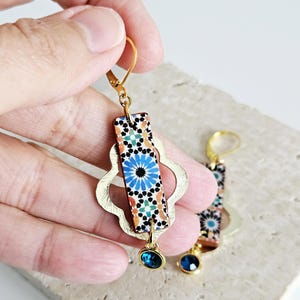 Peut inclure: Boucles d'oreilles dor&eacute;es avec un motif de carrelage bleu et orange, une forme de quadrilobe dor&eacute;e et un pendentif en cristal bleu.