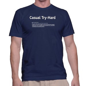 May include: A navy blue t-shirt with white text that reads "Casual Try-Hard" and a definition of the term. The definition reads: "noun | casual try-hard | /'kaʒuəl 'traɪ hɑːd/ : A gamer who wants to appear unconcerned with the outcome of the game, but is actually trying very hard to win, and will be emotionally devastated by failure."