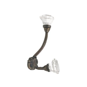 May include: A decorative wall hook with a clear, faceted crystal knob and a curved, antique bronze-colored metal arm. The hook has an ornate, circular base and is designed for hanging items. The overall design is vintage-inspired.