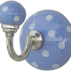 May include: A light blue ceramic wall hook with white polka dots. The hook has a silver-colored metal base and a rounded top. The hook is designed to be mounted on a wall for hanging items.