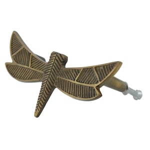 May include: A bronze-colored dragonfly-shaped cabinet knob. The knob features detailed wing patterns and a screw for attachment. The dragonfly is a decorative element for furniture and home decor.