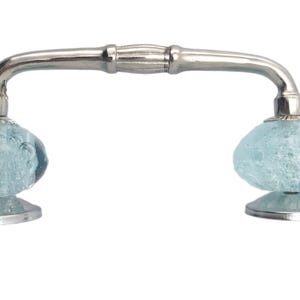 May include: A silver cabinet pull with two light blue, textured glass knobs. The knobs are oval-shaped and sit on a silver base. The handle is a curved, silver bar.