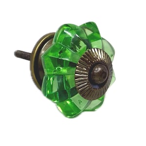 May include: A decorative cabinet knob with a faceted, flower-shaped green glass design. The knob features a bronze-colored metal base and screw for easy installation. This hardware adds a touch of color and style to furniture.
