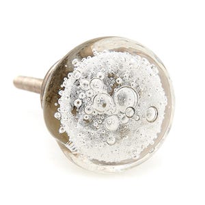 May include: A clear glass cabinet knob with a silver metal stem. The knob is round with a bubbly, frosted interior. The bubbles vary in size, creating a unique, decorative effect. Ideal for furniture upgrades.
