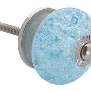 May include: A decorative cabinet knob with a light blue, bubble-filled glass design. The knob has a silver-colored metal base and a threaded screw for installation. The knob's round shape and unique texture add a decorative touch.
