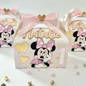 K&ouml;nnte beinhalten: Drei rosa und goldene Geschenkboxen mit Minnie Mouse-Motiven. Jede Box hat einen rosa Schleifen-Griff und ein goldenes Herz-Muster. Die Boxen sind mit einem Minnie Mouse-Charakter, einer goldenen Zahl eins und dem Namen "Natalie" verziert.
