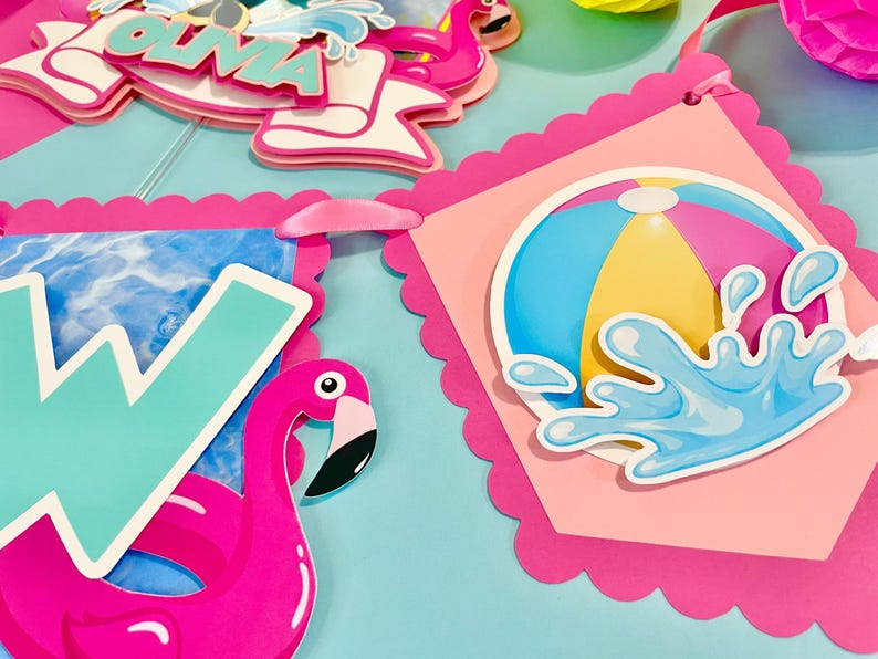 May include: A decorative party banner featuring scalloped pink edges, a large teal letter W, a bright pink flamingo, and a circular graphic of a colorful beach ball with a blue water splash effect. The design includes layered paper cutouts.