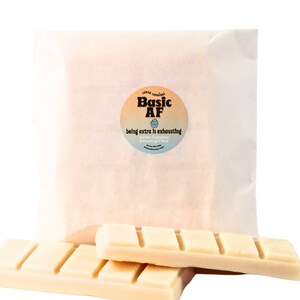 May include: Two white wax melts in a white paper bag with a sticker that says "Basic AF" with a cupcake graphic and the text "being extra is exhausting - Vanilla Cupcakes & Keeping it Real".