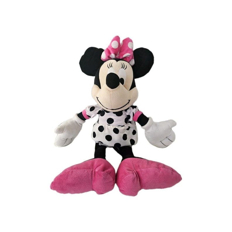 Peut inclure: Une peluche Minnie Mouse, avec une t&ecirc;te et des oreilles noires, un n&oelig;ud rose &agrave; pois blancs et une robe assortie. La poup&eacute;e a des gants blancs, des jambes noires et de grands pieds roses. La poup&eacute;e est debout.