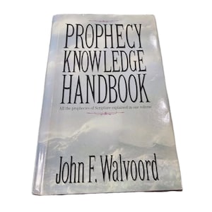 以下が含まれることがあります： ジョン・F・ウォルヴァード著のハードカバー本『The Prophecy Knowledge Handbook』。表紙には、水色と白の山岳風景のイラストと黒い文字が描かれています。サブタイトルには「All the prophecies of Scripture explained in one volume」と記されています。