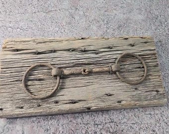 Arnés antiguo rústico con bocado de filete montado sobre madera envejecida, decoración