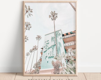 Pode incluir: Um edifício turquesa com uma placa de néon branca que diz "The Beverly Hills" contra um fundo de palmeiras e céu azul.
