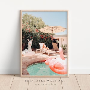 Könnte beinhalten: Eine Frau entspannt sich auf einer Liege am Pool mit einem rosa Flamingo-Schwimmring und einem Lama-Schwimmring. Der Pool ist von üppigem Grün und einem Sonnenschirm umgeben.