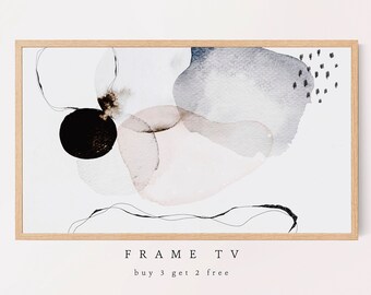 May include: Abstract watercolor painting in shades of gray, pink, and black with a black circle in the center. The painting is framed in a light wood frame. The text "FRAME TV" and "buy 3 get 2 free" is printed below the frame.