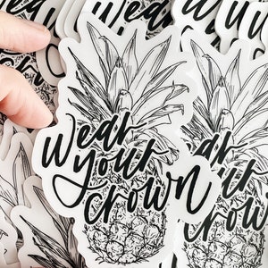 May include: Black and white illustration of a pineapple with the text "Wear your crown" printed on it. The image is on a white background with the website carlyallred.com printed at the bottom.
