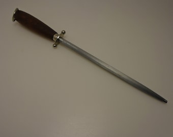 May include: A knife sharpening steel with a dark wooden handle and a silver-colored metal rod. The handle has a silver bolster and a rounded end. The rod tapers to a point. A kitchen tool for maintaining knife sharpness.