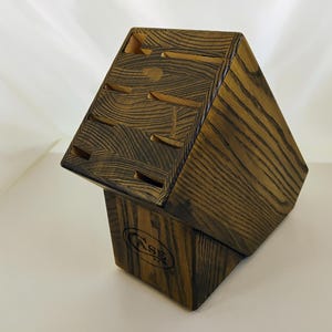 May include: A dark brown wooden knife block with a prominent wood grain pattern. The block features multiple angled slots for knife storage and displays the word CASE branded in black ink on the front face of the base section.