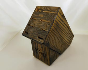 May include: A dark brown wooden knife block with a prominent wood grain pattern. The block features multiple angled slots for knife storage and displays the word CASE branded in black ink on the front face of the base section.