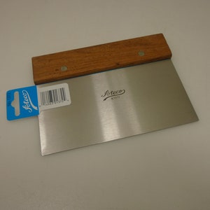 May include: A stainless steel dough scraper with a wooden handle. The scraper has a blue label with the text "Arteco" and a barcode. The handle is brown and has a small metal rivet.
