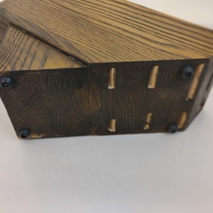 May include: A dark brown wooden knife block with a visible wood grain pattern. The base features four small black circular rubber feet attached to the bottom surface, providing stability and preventing the block from sliding on flat surfaces.